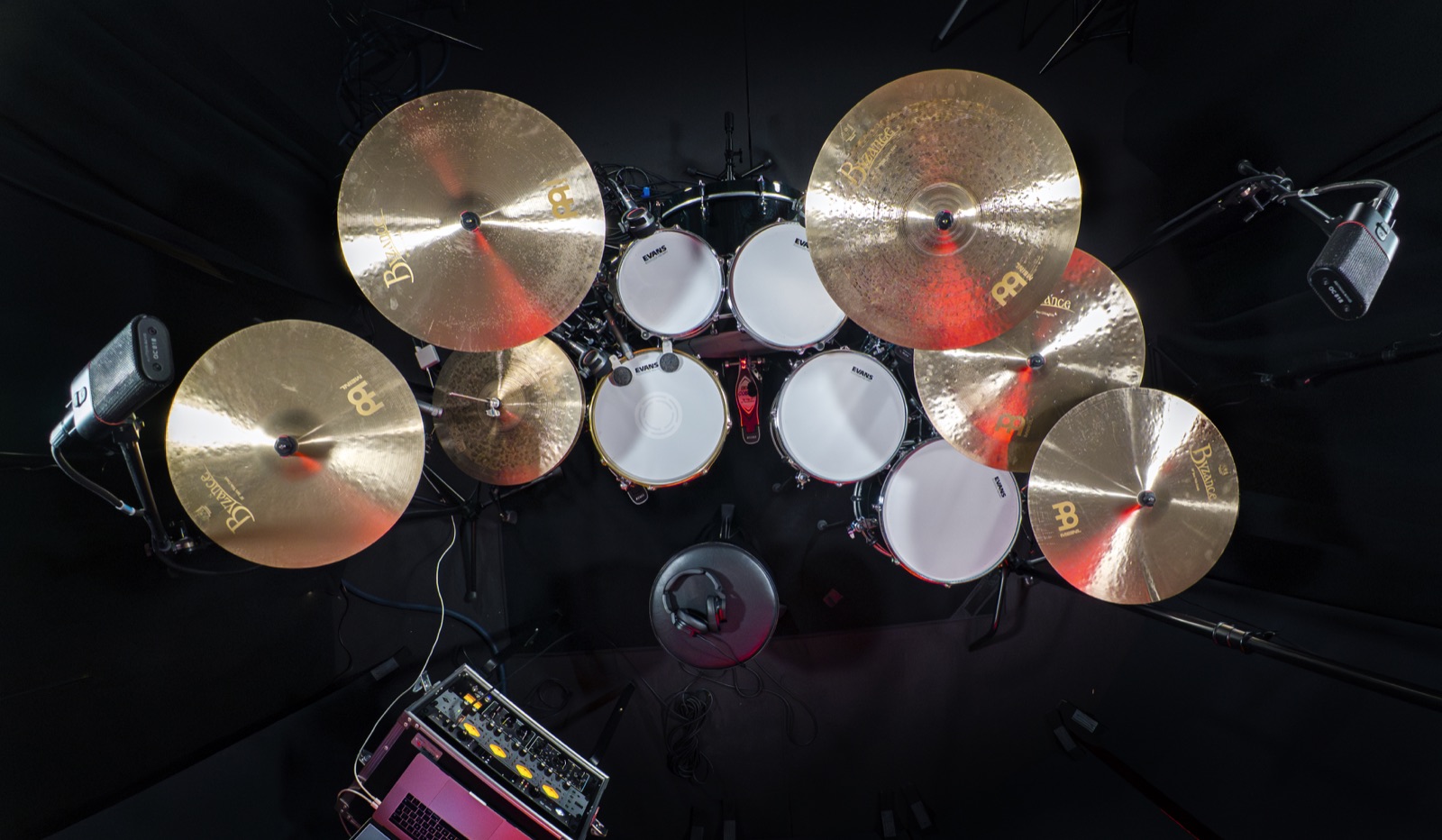 Overhead view of a white-head drum kit and cymbals under red light